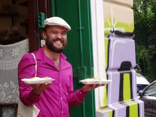 de gids komt naar buiten met twee borden vol pierogi, tijdens de Polish Food Tour in Krakau