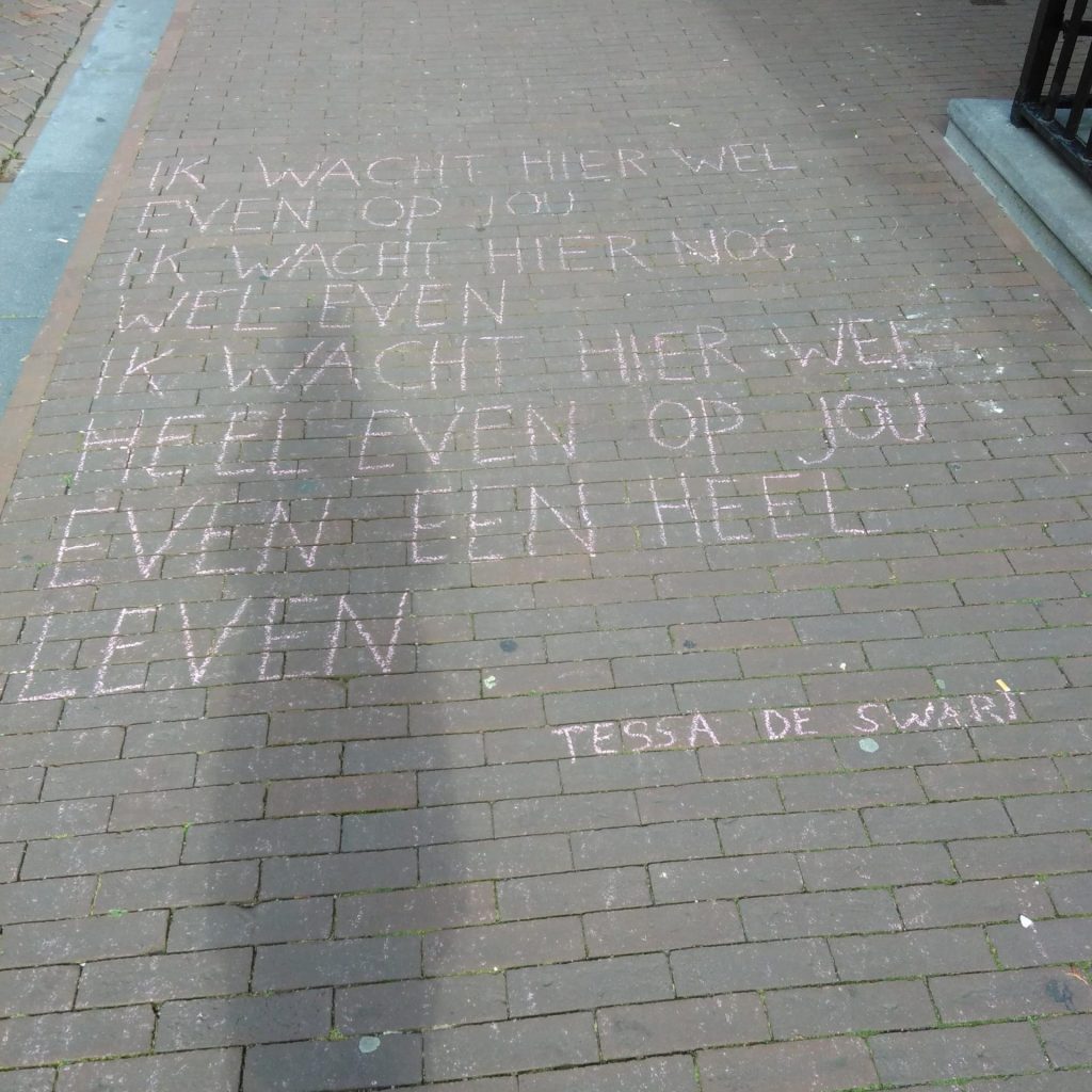 Een stoepkrijtgedicht. "Ik wacht hier wel, even op jou, ik wacht hier nog, wel even, ik wacht hier wel, heel even op jou, even een heel, leven." van Tessa de Swart