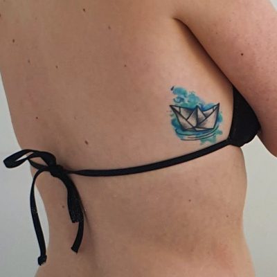 een foto van mijn tattoo: een papieren bootje in het water